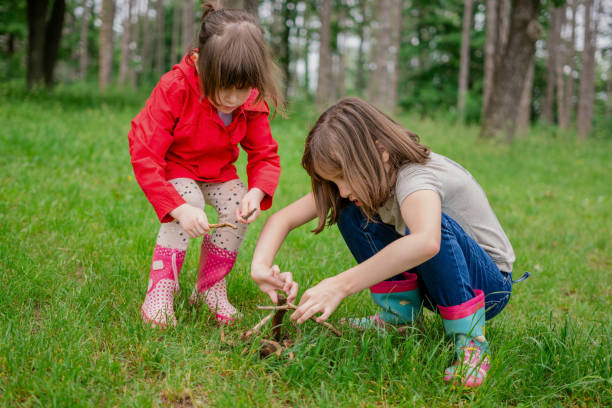 Two girls are collect branches for camping in the forest.