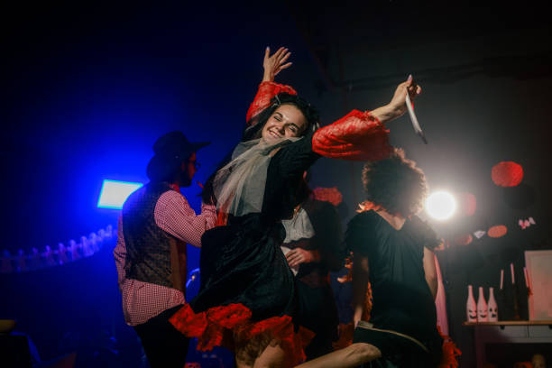 Portrait of charming young woman dancing in costume during a fun Halloween party with friends. She is looking at camera, smiling joyfully with confidence.