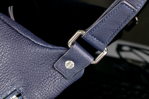 Part of a blue leather bag on a black background. Leather goods.