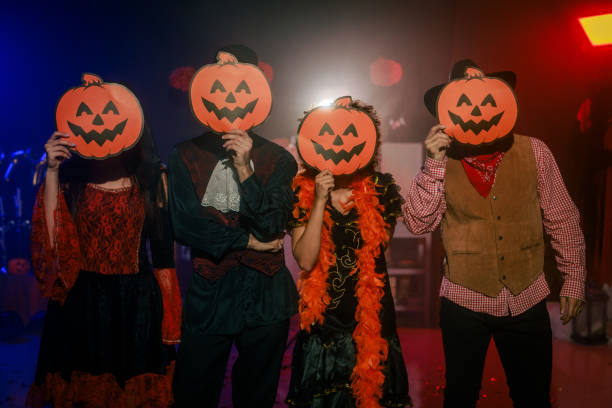 istock Friends putting Jack o' Lantern masks over faces during a Halloween party 2040139332