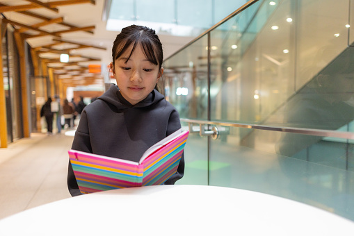 Teenage girl reading book in city