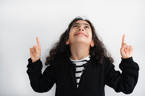 Thumbs up. One cute smiling preschool girl in beautiful blue dress posing isolated over white studio background. Childhood, fun, emotions, facial expression concept.