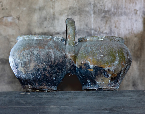 Antique pottery. Two old clay pots connected by handle close-up on grey background