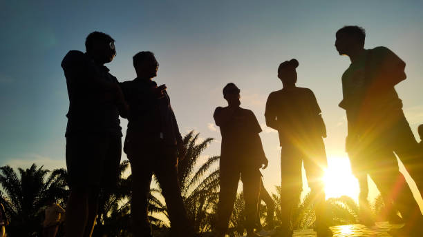 Kuaro Kalimantan Timur, Indonesia 26 February 2024. silhouette of several people chatting against a background of sunlight