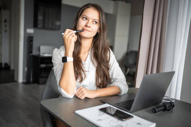 istock Portrait of young woman using laptop in home workplace, writing notes, female student learning and watching online webinar or listening audio course, e-learning education concept. 2040256668