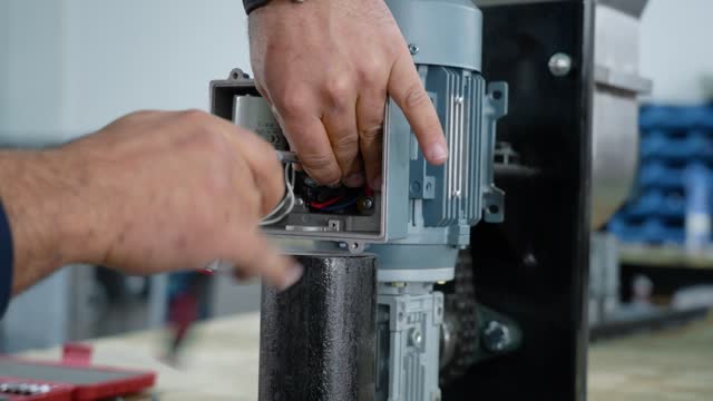 A worker installs bolts into an electric motor