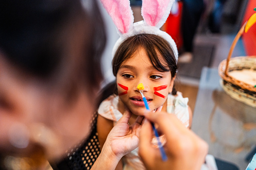 Girl with bunny painting on face during Easter holiday at home