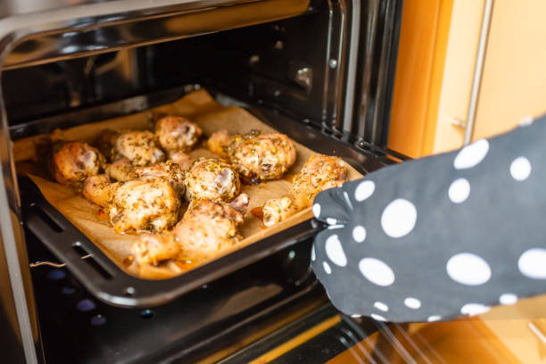 istock Woman's hand pulls out baked chicken legs from the oven.Soft focus,selective focus. 2040271702