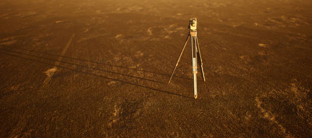 Land surveyor on tripod standing on wide open flat landscape.