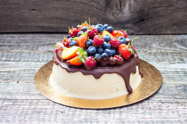 Delicious cheesecake with melted chocolate, apples, strawberries, blueberries, peaches, raspberries and kumquats on the top, rustic background
