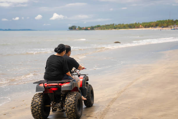 istock mature Couple riding a Quad ATV down the Beach 2040281326