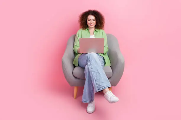 Full length body photo of optimistic cheerful young woman team lead using new macbook pro in dormitory isolated on pink color background.
