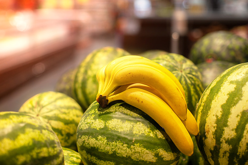 A branch of ripe bananas and a bunch of watermelons are on sale.