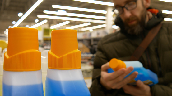 A male buyer choosing detegent or solvent bottle in a hardware store