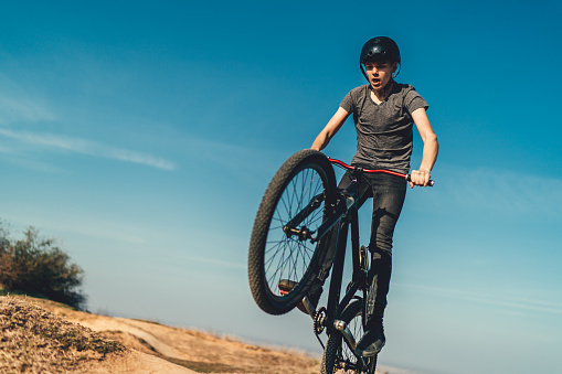 Young male mountain biker jumping mid air on rural pump track