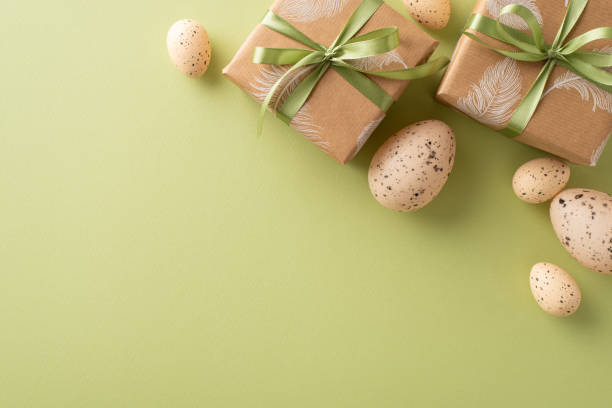 istock Cozy Easter arrangement concept. Top view of craft gift boxes, and beige quail eggs, set on an olive green ground with a vacant area for text or adverts 2040342082