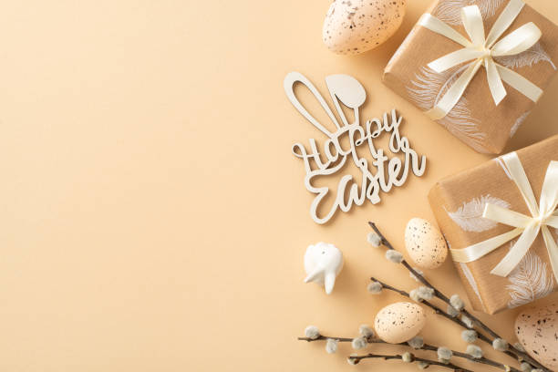 istock Charming Easter display idea. Overhead shot of craft-wrapped presents, Happy Easter text, speckled quail eggs, ceramic bunny, pussy willow branches, all set on soft beige backdrop with space for copy 2040342092