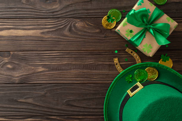 istock Enchanted St. Patrick's setup, featuring top view shamrocks, a green top hat, golden coins, present, a lucky horseshoe, and glitter, all laid out on a wooden surface for your message 2040342113