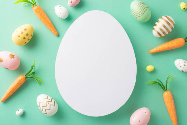 istock Easter creativity theme: Overhead shot showcasing vibrant eggs, and sweet carrots for the Easter Bunny on a turquoise backdrop, featuring a blank egg-shaped space for messages or ads 2040342393