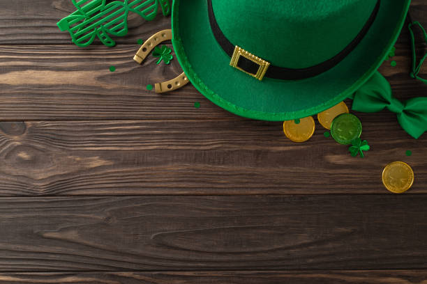 istock Imaginative St. Patrick's view from top, with shamrocks, folklore hat, bullion coins, goodies, novelty eyepieces, bowtie, good luck horseshoe, adornments, wooden canvas, leaving margin for text 2040342637