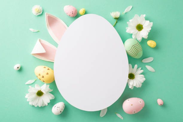 istock Easter project layout: Top view of assorted eggs, endearing rabbit ears, and chamomile blooms on a sea-green base, with a vacant egg-shaped frame for notes or marketing 2040342641