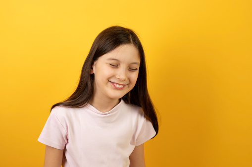 Happy young caucasian girl isolated over yellow background.
