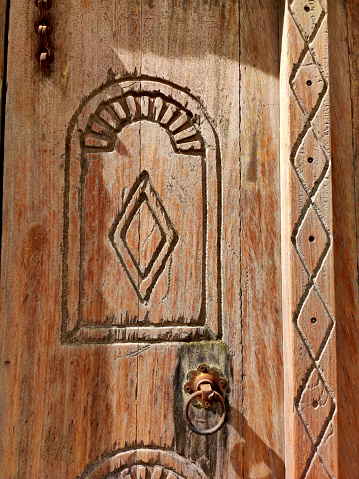 Dubai, UAE - January 26, 2024: Carved patterns on a wooden door in the Old City of Dubai. Traditional Arabic architecture details. Recreated tourist attraction