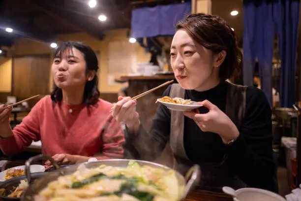 Female friends eating “motsunabe” Japanese food for dinner