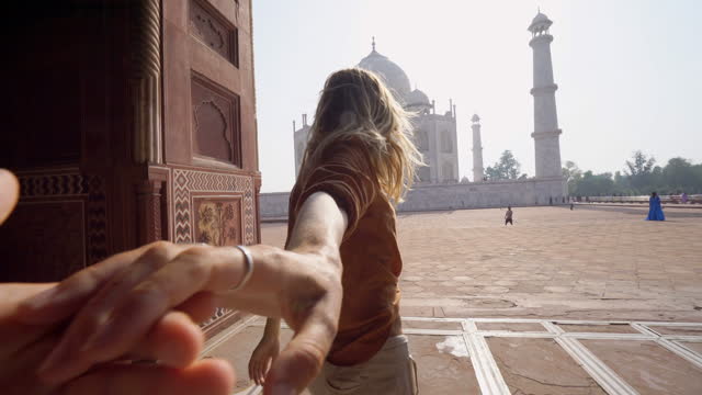 Follow me to the Taj Mahal, India. Female tourist leading boyfriend to there magnificent famous Mausoleum in Agra. People travel concept
