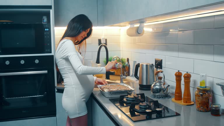 Pregnant woman sprinkles the finished pie with pastry crumbs