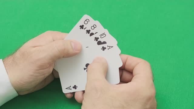 man hand opens poker combination of flash of one black suit of clubs,  close-up, slow motion