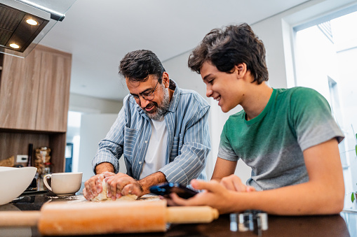 Father and son cooking together at home