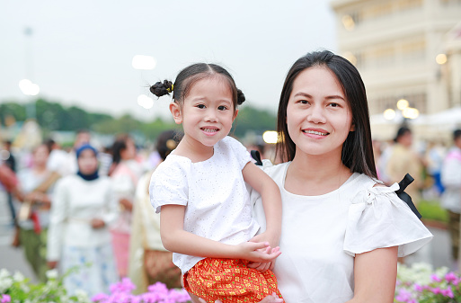 Adorable Asian child girl and mom in traditional thai dress in the public garden.