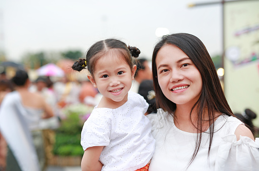 Adorable Asian child girl and mom in traditional thai dress in the public garden.