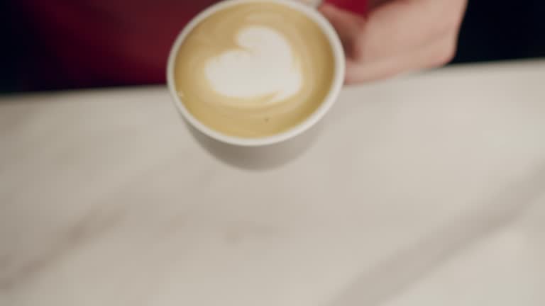 Barista make cappuccino and pouring milk froth into drink with heart shape