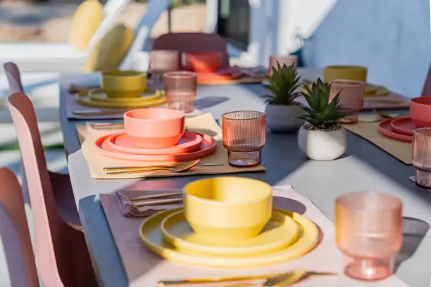 Set dining table outdoors with colorful bowls, plates, glasses, and silverware