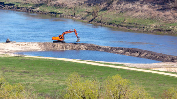 Orange excavator works on the river bank.