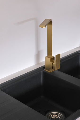 Brass mixer tap on a black granite sink.