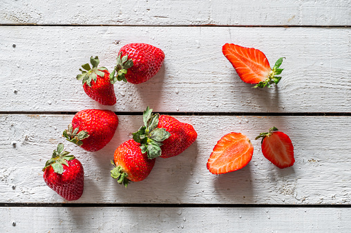 Several Spanish strawberries, on a white wooden background, rich in fiber, combat constipation and regulate cholesterol, they can cause allergies