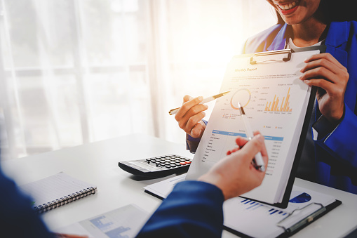 Colleagues discuss business charts and analytical prices using calculators and laptops to calculate finance, taxes, accounting, statistics, teamwork concept. Calculate personal taxes for clients