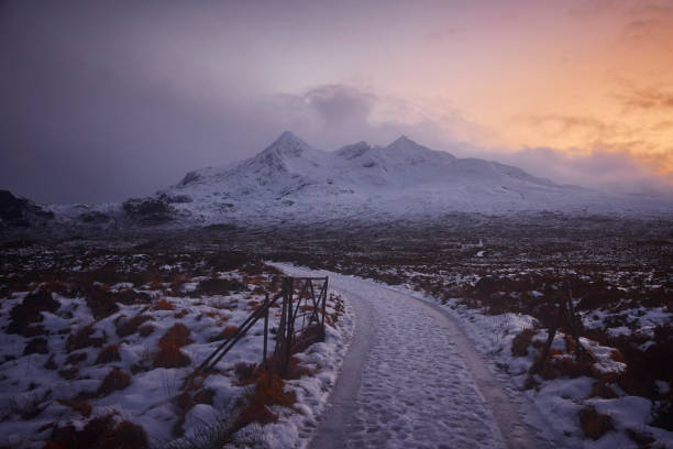 Snow covered road during winter, UK, scotland. In the back you see the mountains of Cuillins during sunset, on Isle of Skye.