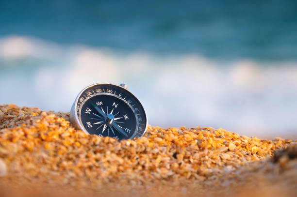 compass on sea sand and place for text. close up of navigation device on sandy beach without people, top view - compass exploration the way forward beach fotografías e imágenes de stock