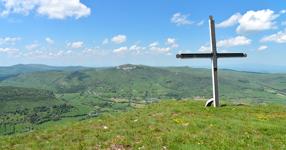 Christian cross on top of a mountain with a magnificent view of a mountainous landscape