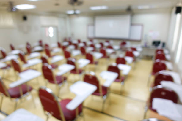 istock Blurred abstract background of examination room with undergraduate students inside. Blurred view of a student doing the final test in the exam room. Blurry view of study chairs in university. 2040516299