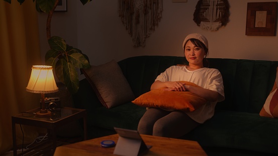 A portrait of a beautiful woman enjoying her time in the living room at home at night.