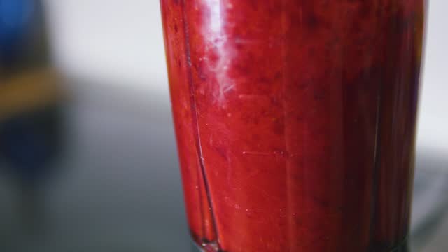Red berry smoothie rotating in blender. Side view.