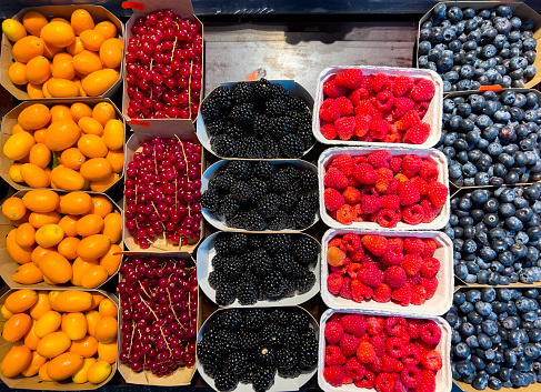 Berries and kumquat fruits spread on a market stall to be used as a background. The concept of healthy eating and delicious recipes.