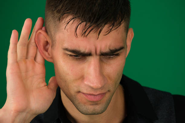 The deaf young man put his hand to his ear, listened. High quality photo