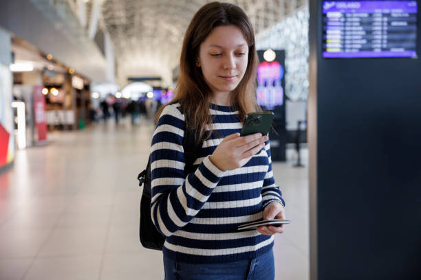 istock Smiling young woman with backpack checking her boarding schedule at the airport 2040540869