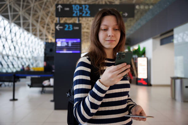 istock Smiling young woman with backpack checking her boarding schedule at the airport 2040540895